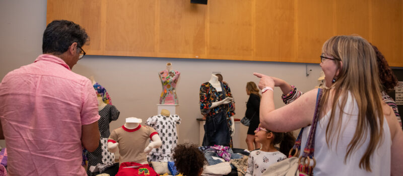 Three adults and two children viewing the textile work with much joy and pointing